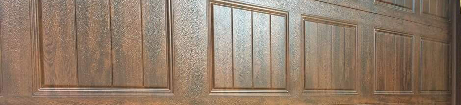 Professional installation of sectional faux wood garage door by technicians