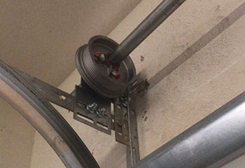 Frayed garage door cables and damaged steel tracks inside Conroe, Texas garage